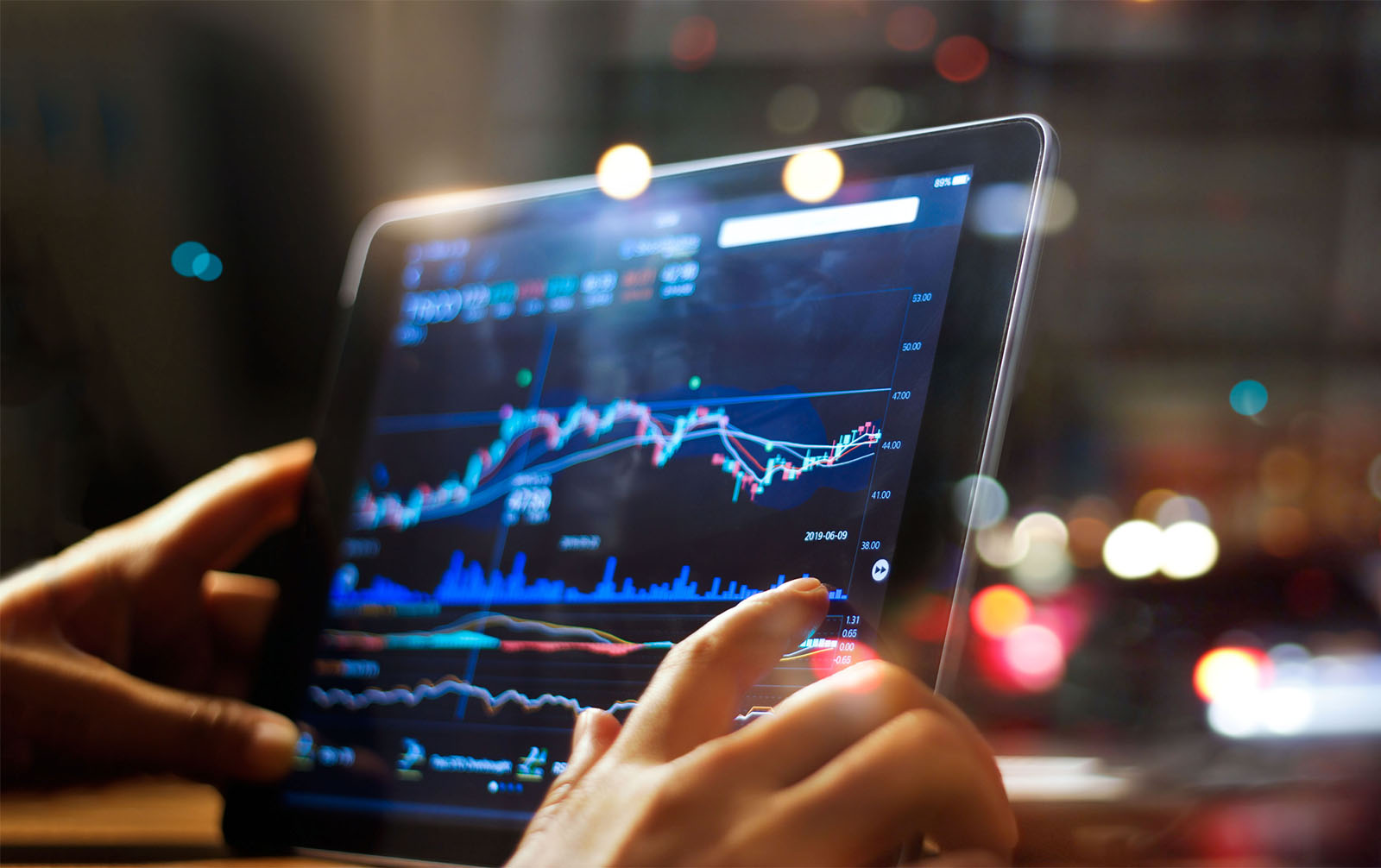 Person checking market data on tablet on night background