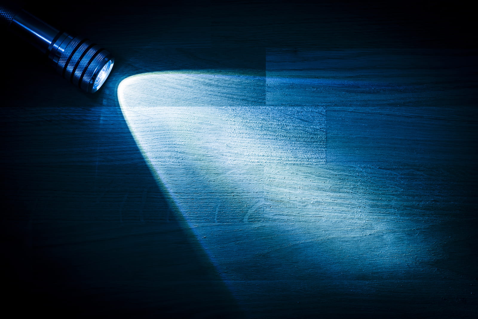 Torch shining a beam of blue light onto a wooden background