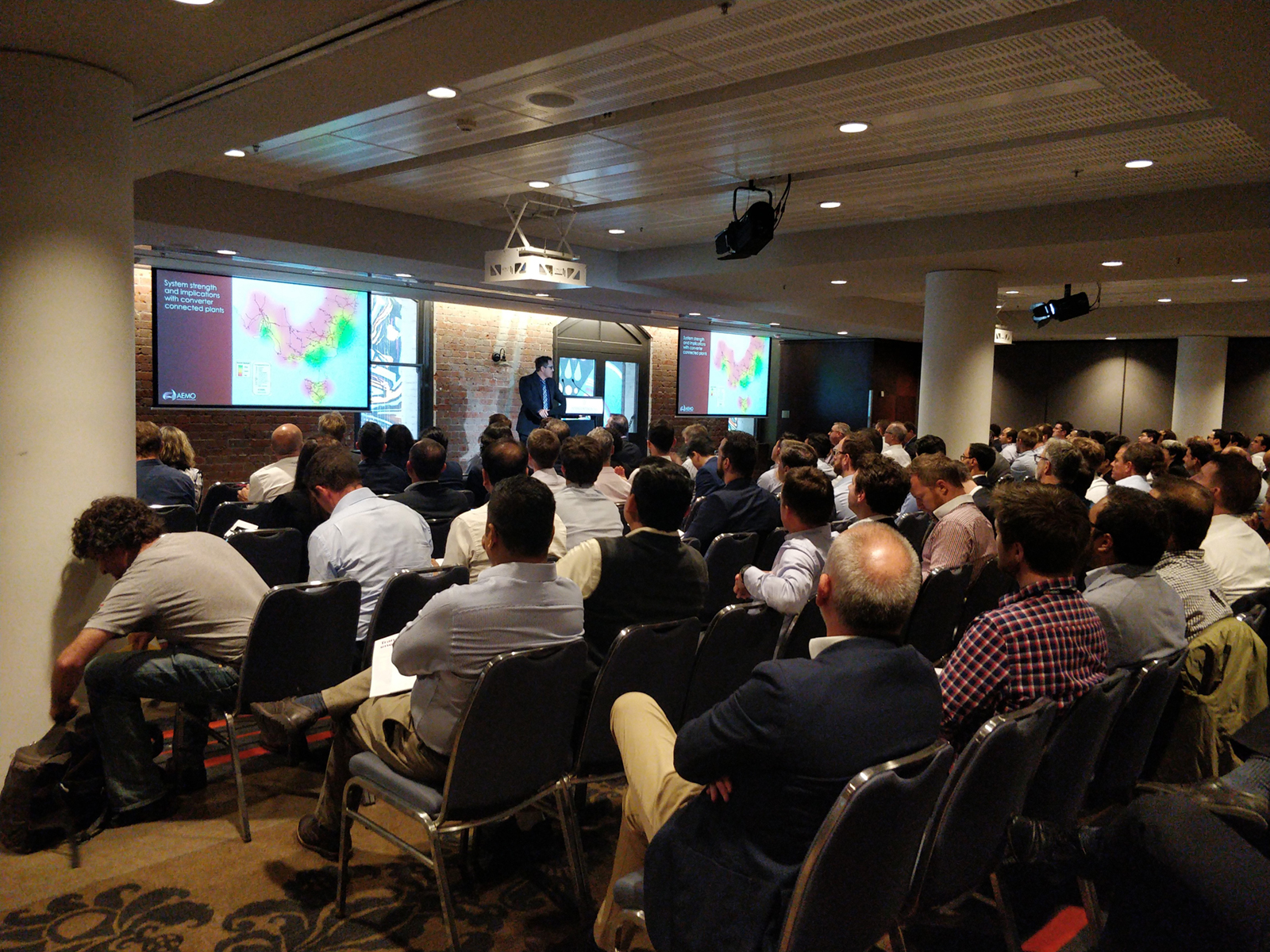 Speaker and presentation in front of seated auditorium audience