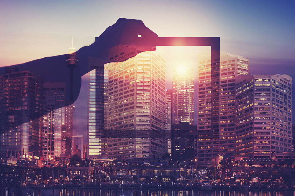 Person holding a picture frame over Sydney skyline at sunset