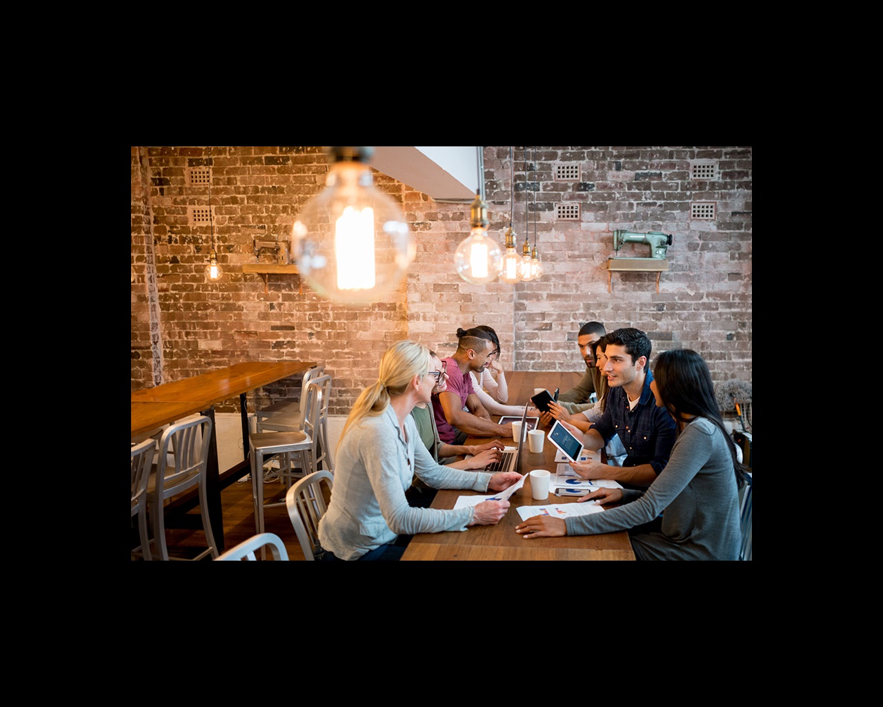 Group of people working at the office sharing ideas and looking very happy with focus on foreground on a lightbulb