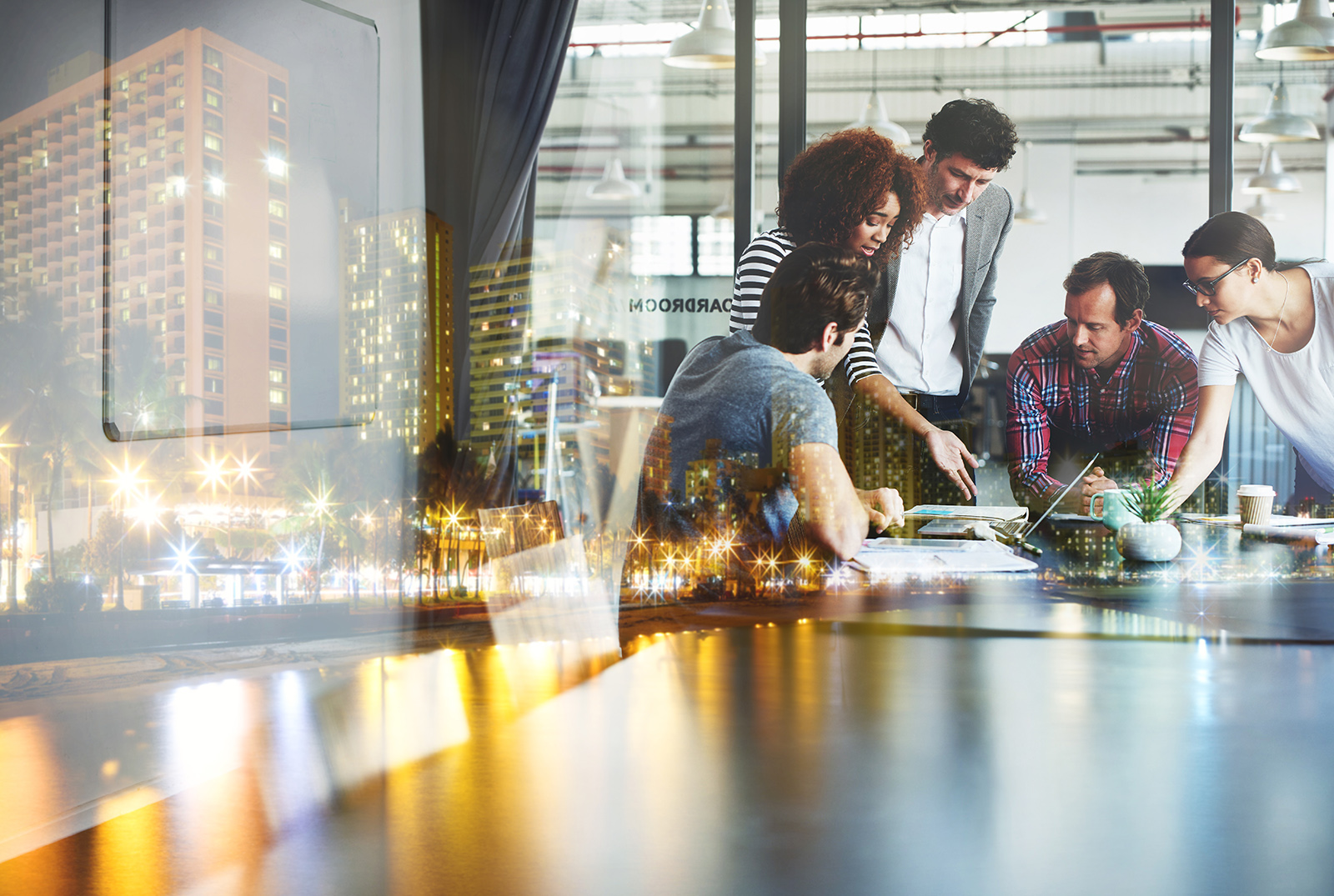 Multiple exposure shot of a business meeting superimposed over a city at night