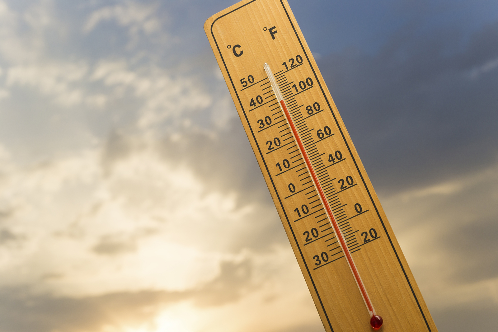 Mercury thermometer with 38 degrees Celsius and the setting sun in the background.